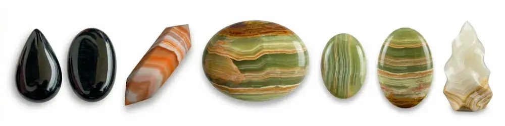 Vista panorámica de una colección de cabujones y formas pulidas de ónice en varios colores y patrones sobre fondo blanco
